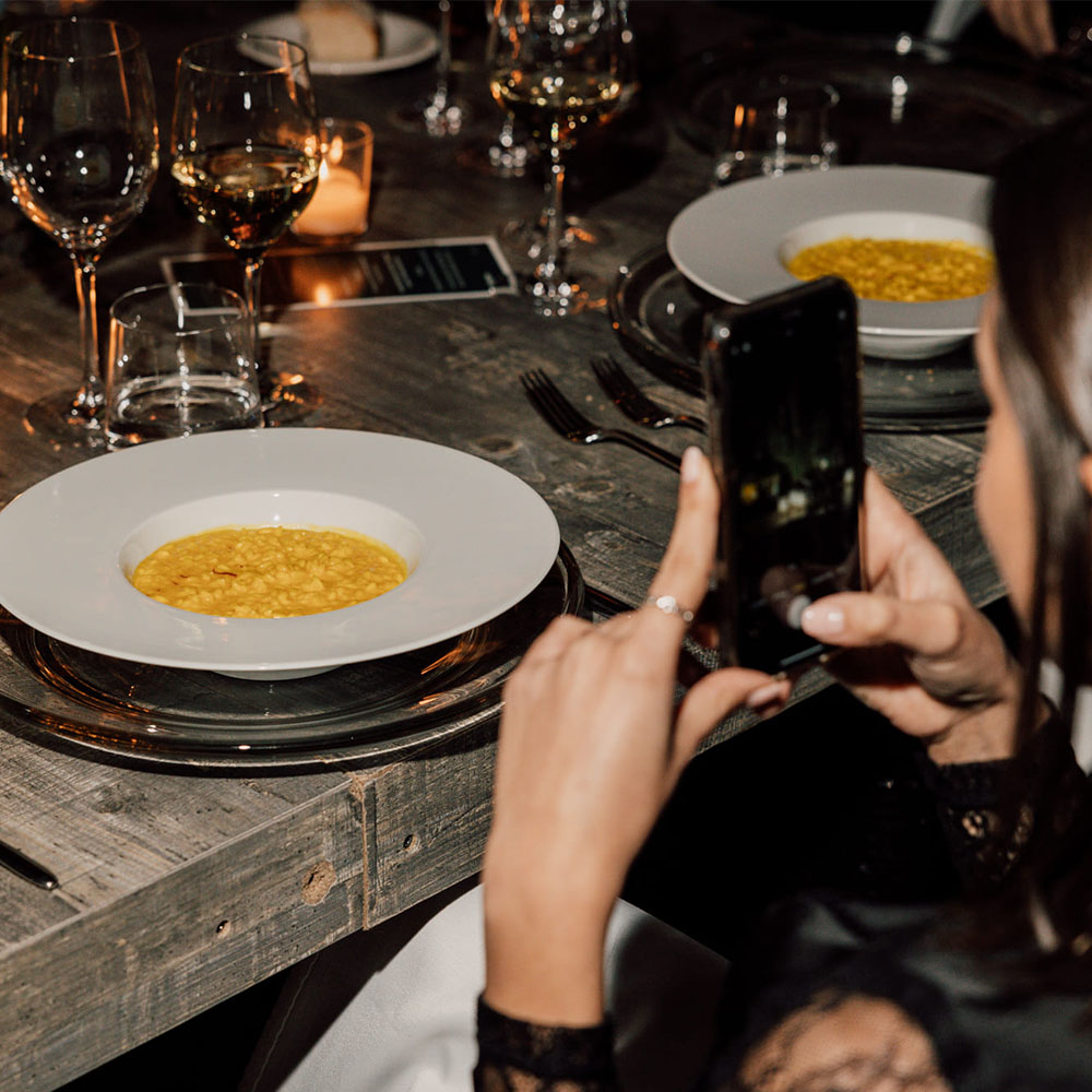 Ragazza che fotografa il piatto di risotto alla milanese