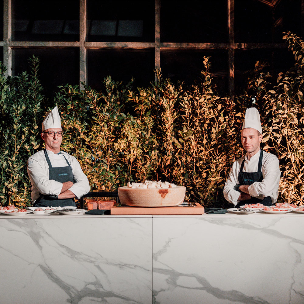Due chef ai lati di una forma di formaggio