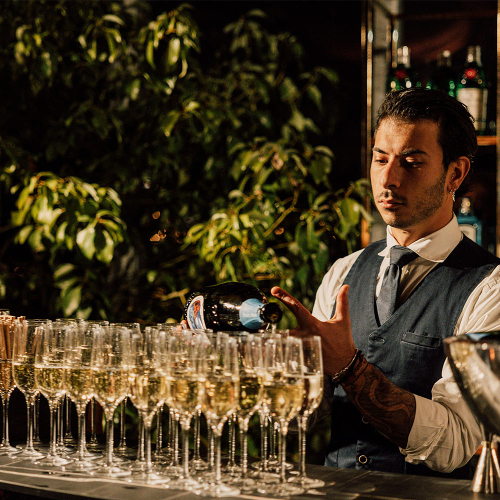 Barman che versa il vino nei bicchieri disposti in fila