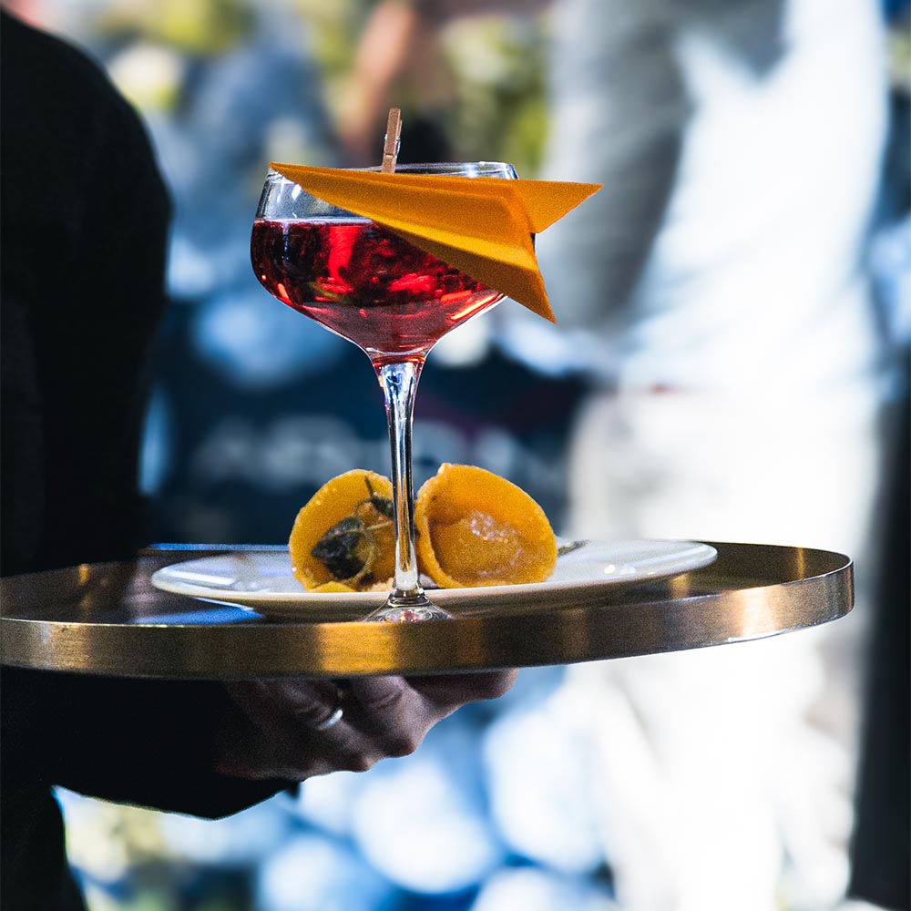 Signature cocktail con aereo di carta e ravioli