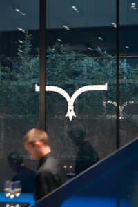 Gruppo Spuma Logo Larusmiani in vetrina e cameriere che scende le scale