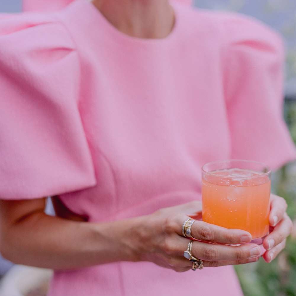 Ragazza in abito rosa che tiene in mano un cocktail