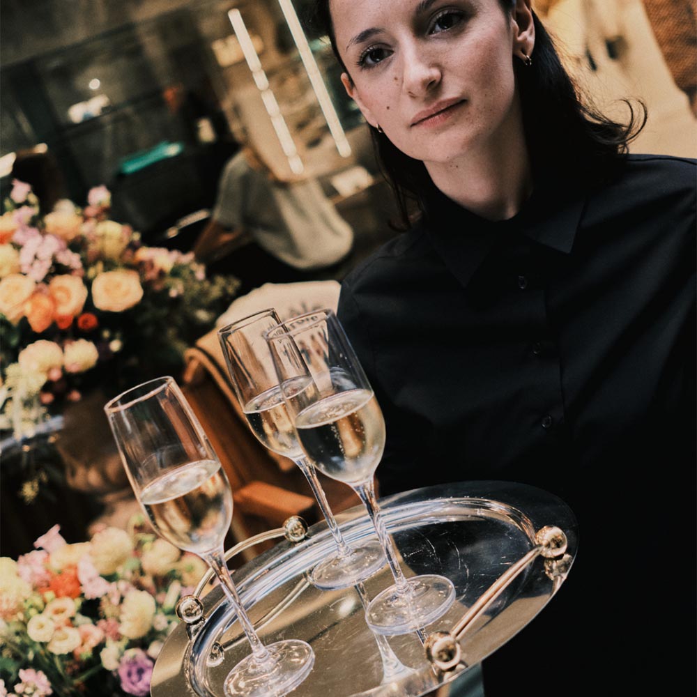 Cameriera con flute di vino su un vassoio