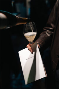 Gruppo Spuma Vino versato in un calice con brochure Nicolo Romano