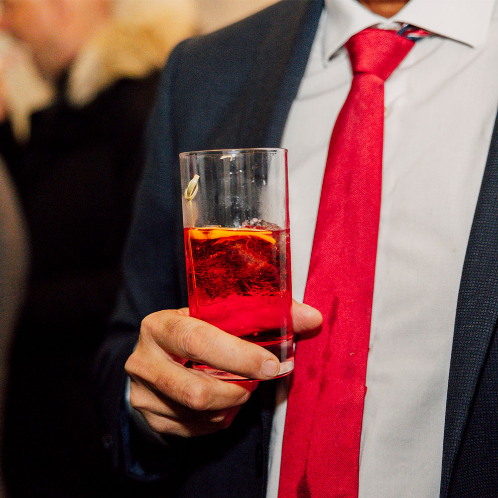 Uomo in abito che sorregge un cocktail