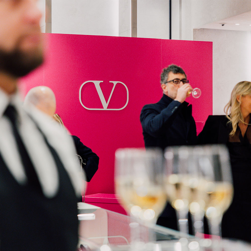 Cameriere e ospiti davanti al panel Valentino
