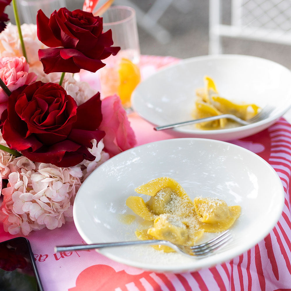 Piatti di ravioli sul tavolo con rose accanto