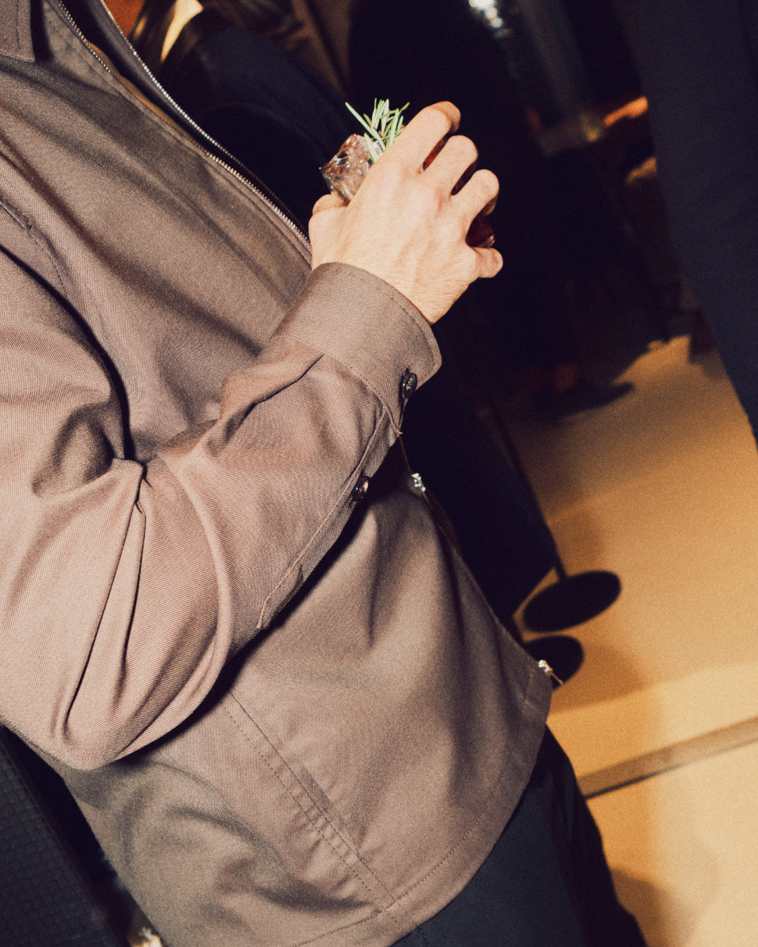 Uomo in giacca marrone con un drink in mano
