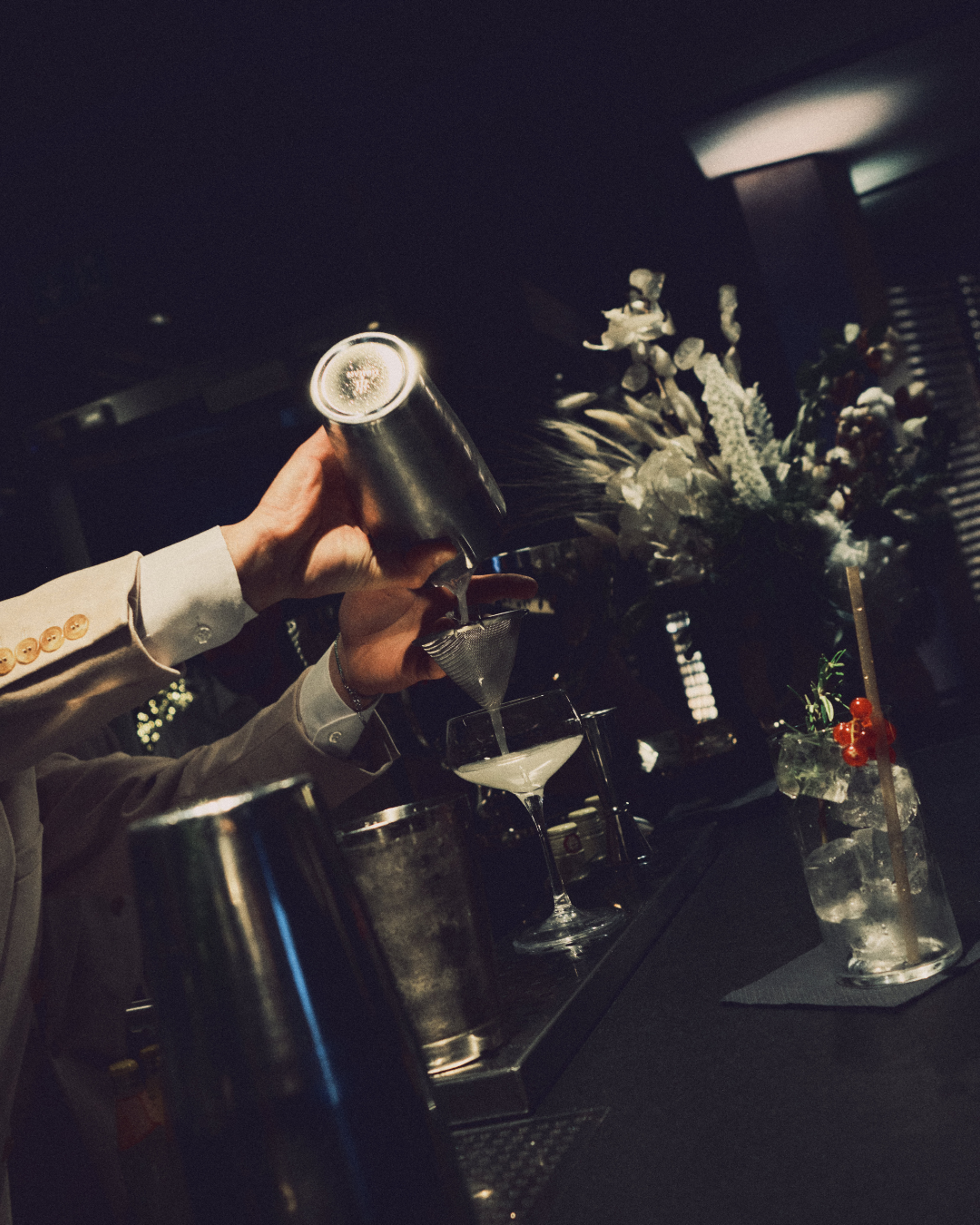Barman che versa un cocktail dallo shaker in un bicchiere
