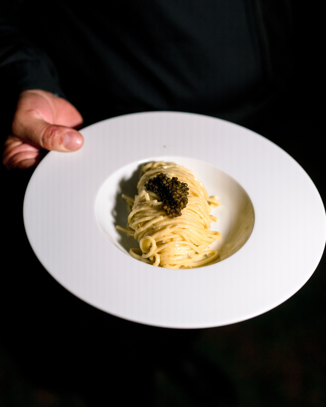 Tagliolino al lime e caviale su sfondo nero