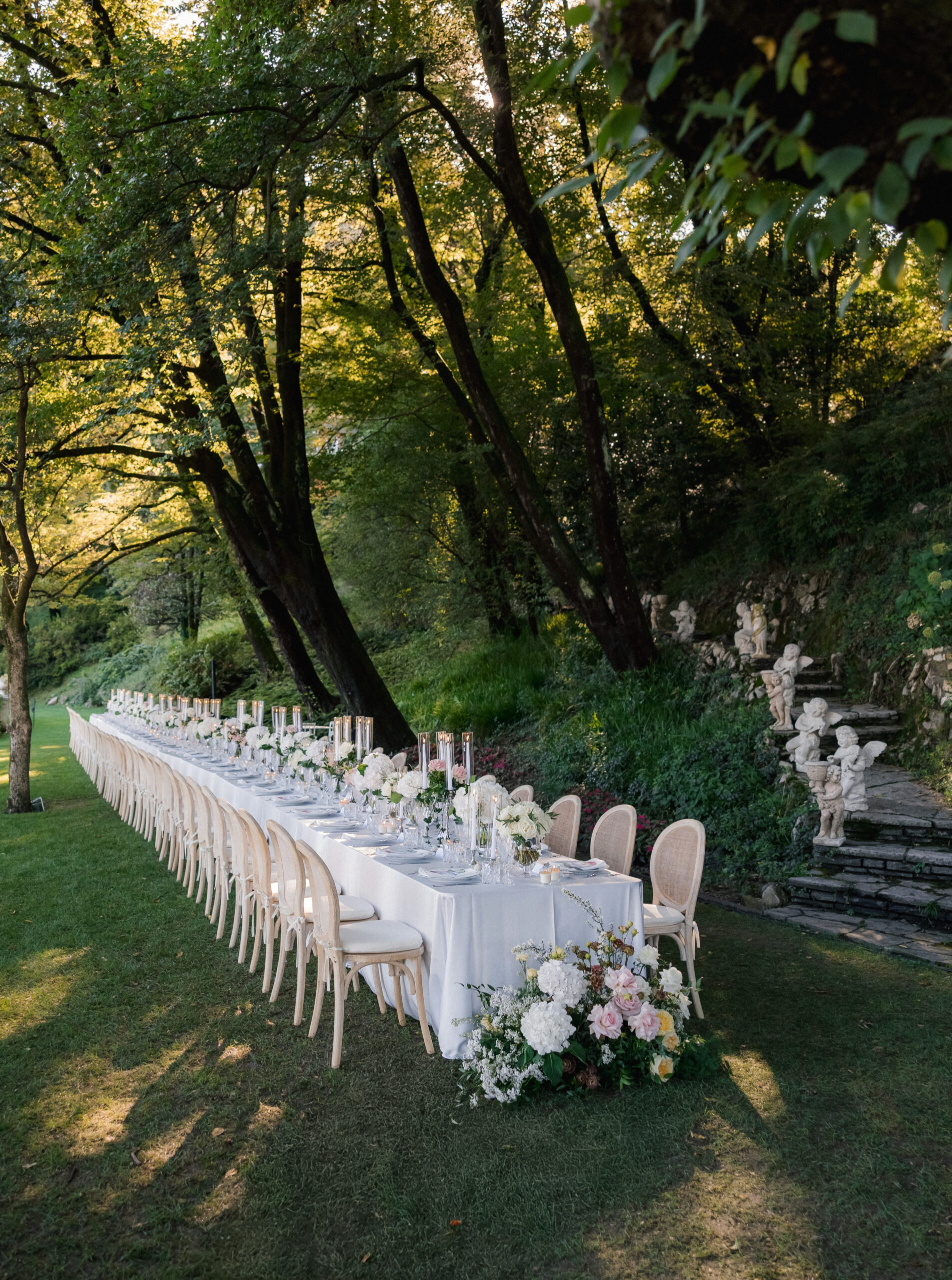 Tavolo bianco con mise en place sotto gli alberi
